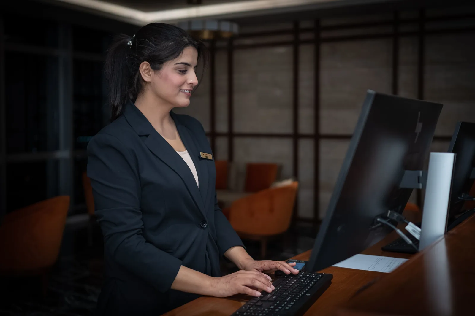 A female receptionist working at a hotel front desk in Islamabad, Pakistan. Hospitality SEO tools compared for teams without a dedicated analyst