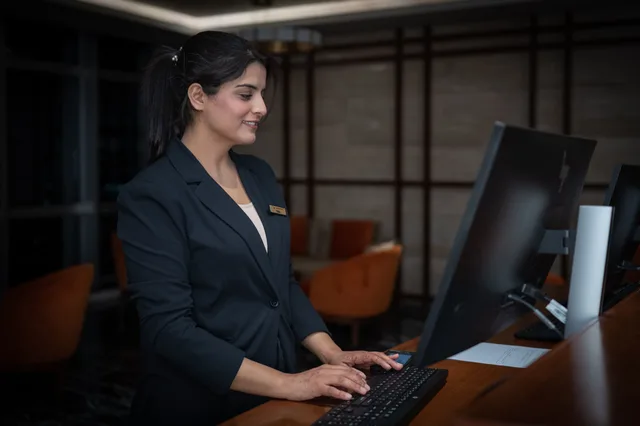 A female receptionist working at a hotel front desk in Islamabad, Pakistan. Hospitality SEO tools compared for teams without a dedicated analyst